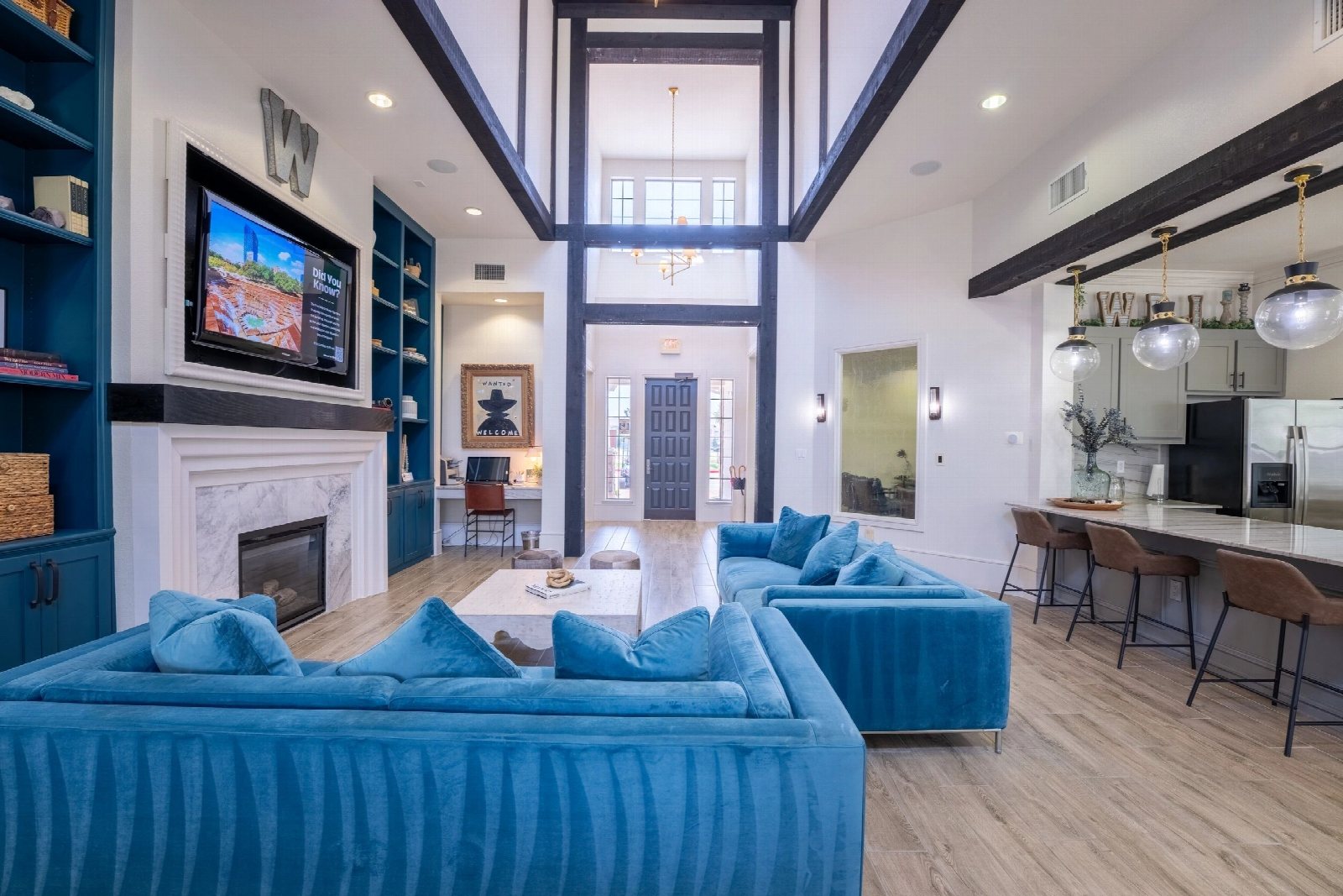 Double-height living room with navy built-in shelving and a blue velvet sectional.