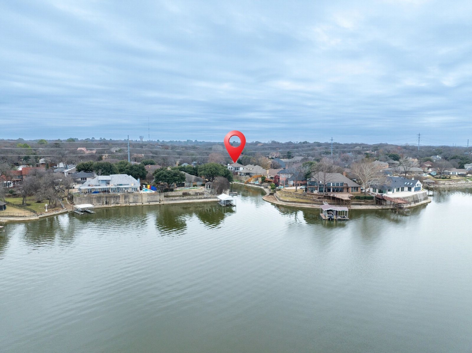 Aerial view over a lake with a red location pin marking a waterfront property.