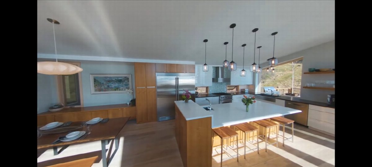Frame from an indoor fly-through: a modern kitchen with pendant lights above an island.