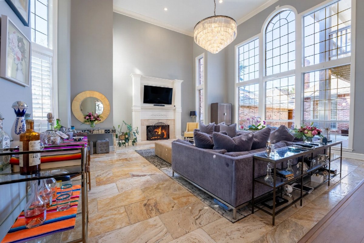 Two-storey living room with a chandelier, arched windows and a fireplace.