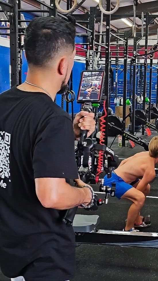 Videographer operating a gimbal-mounted camera while filming in a gym.