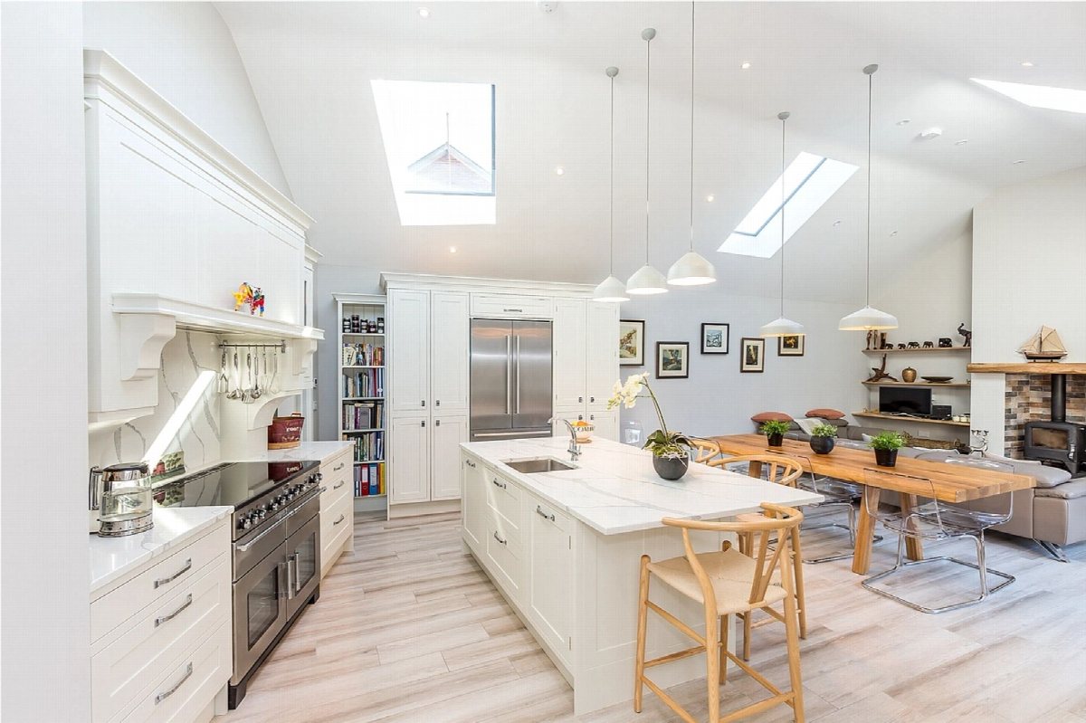 Bright modern kitchen with white cabinetry, a wooden island and skylights.