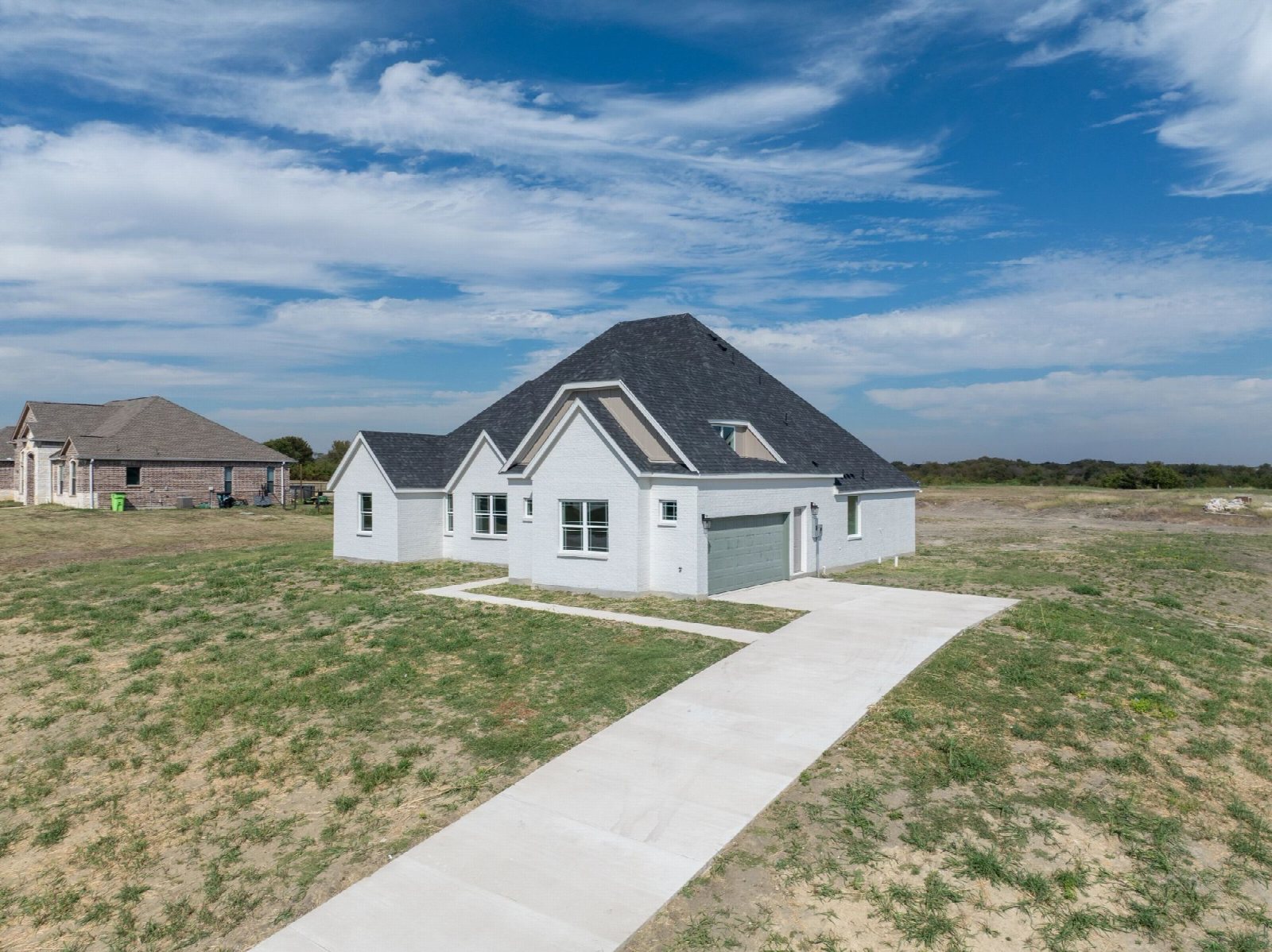 Low aerial view of a newly built single-storey house on a cleared lot.