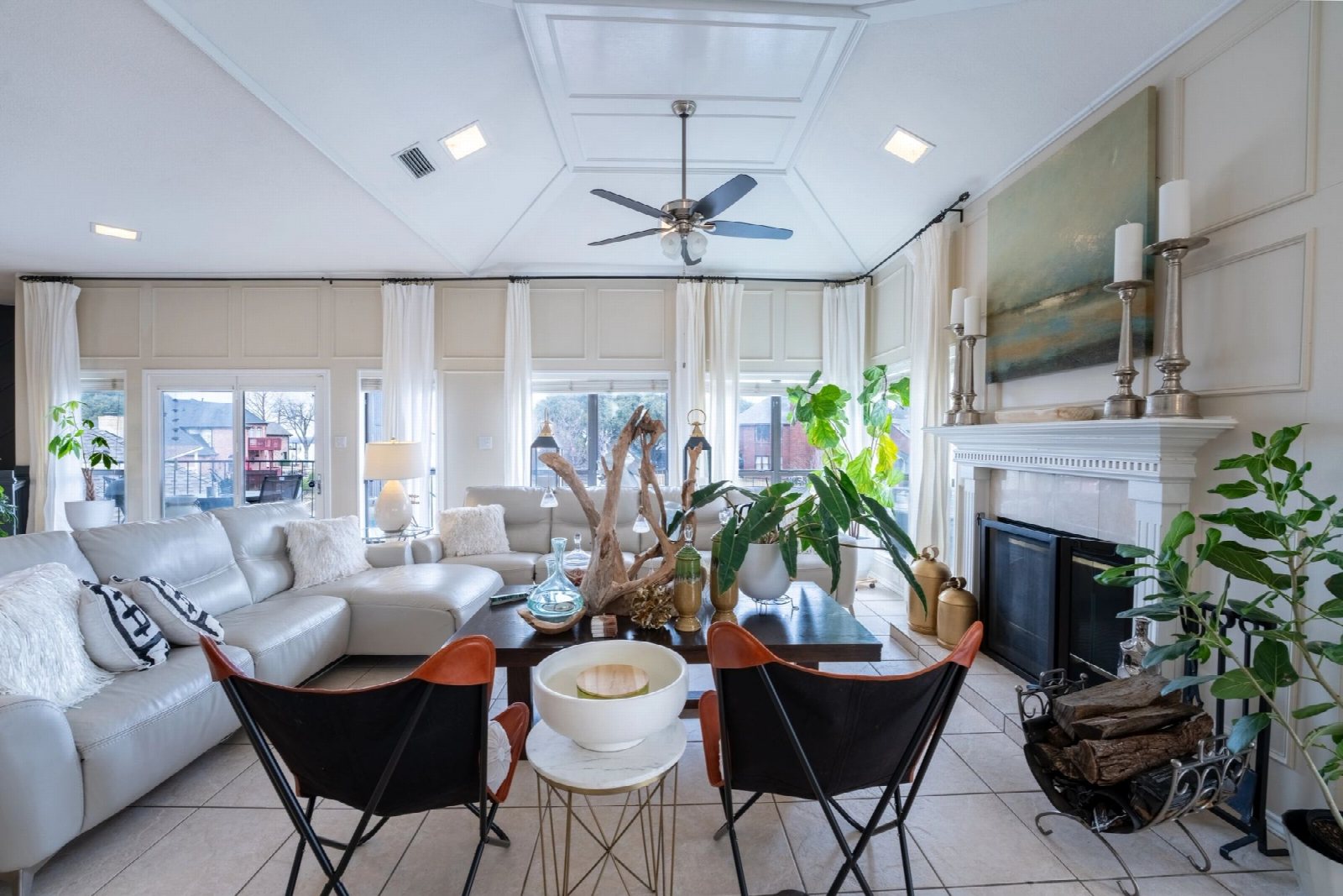 Bright living room with a white sectional, a driftwood centrepiece and a fireplace.