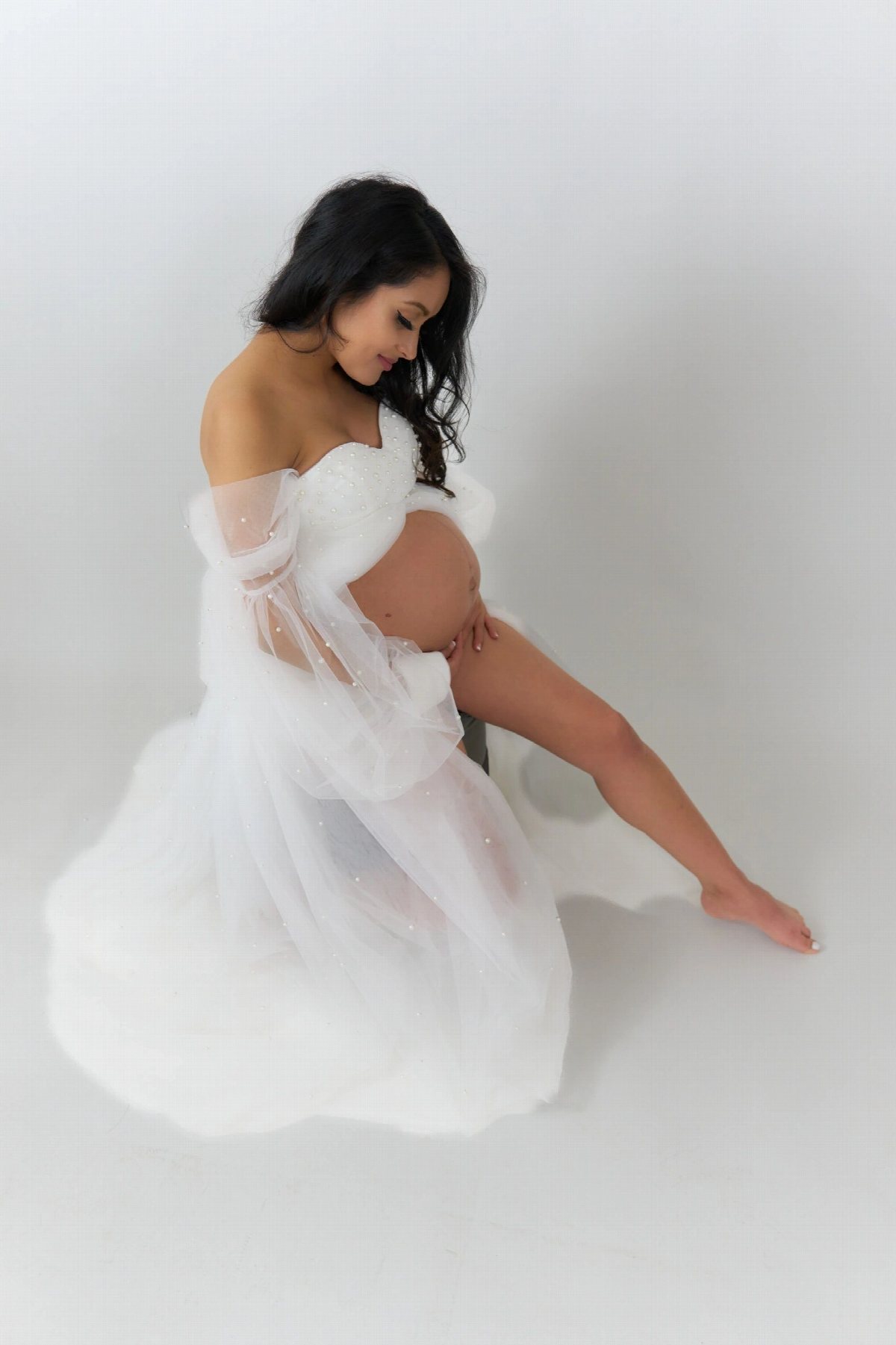 Portrait of a person in a layered tulle gown against a pale backdrop.
