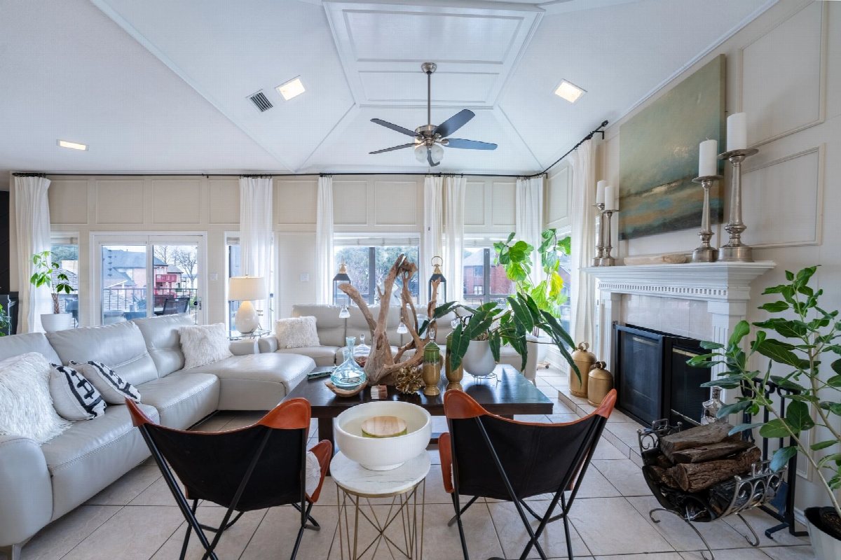 Sunlit living room with vaulted ceiling, white sofas and a fireplace.